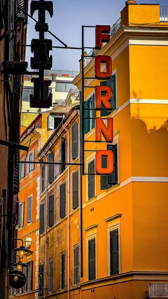 イタリアのオレンジの建物に対して捕獲された場所の名前を持つ道路標識の垂直 — ストック写真