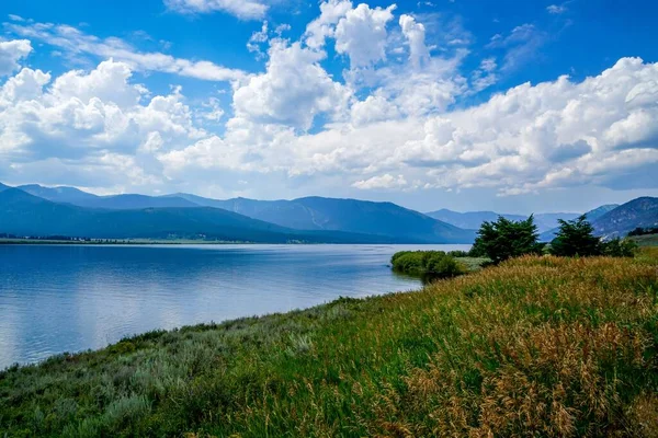 Krásný Záběr Jezera Obklopeného Horami Proti Modrému Zamračenému Nebi Slunečného — Stock fotografie