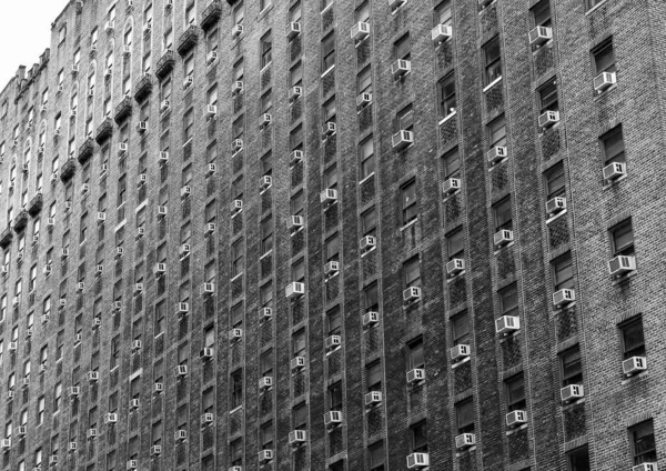 グレースケールの空調ユニットと同様の窓に覆われた大きな建物の低角度ショット — ストック写真