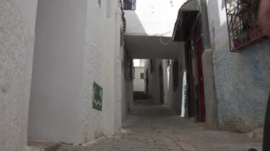 Dar bir sokakta yürüyen genç bir erkek.