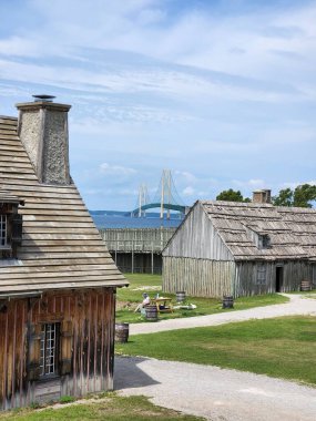 Mackinaw, Michigan, ABD 'deki Michilimackina Kalesi' nde küçük binaların yanında oturan bir kadının dikey görüntüsü.