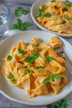 Masanın üzerinde iki kapaklı balkabaklı makarna tagliatelle tabağı.