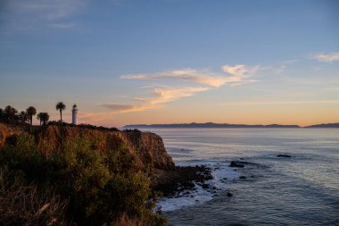 Gün batımında sahilde bir deniz feneri