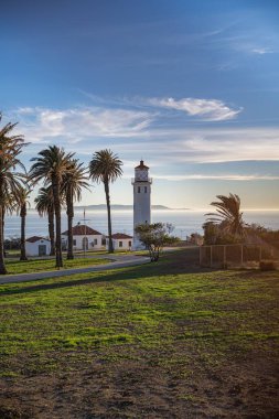 Gün batımında kıyıda bir deniz fenerinin dikey görüntüsü.