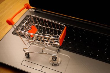 Not defterindeki bozuk para yığınının üzerinde minyatür sepetli online alışveriş konsepti