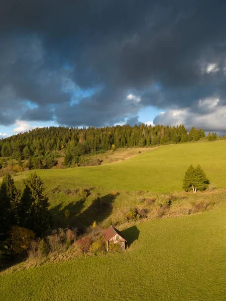 Stock image An aerial view of a hut near trees in a green field under a cloudy sky