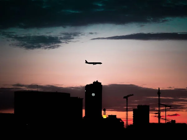 Eine Silhouettenansicht Von Gebäuden Unter Einem Fliegenden Flugzeug Mit Rotem — Stockfoto