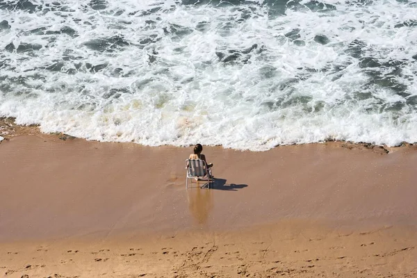 在靠近水边的海滩上的躺椅上拍摄的一张女性高角照片 — 图库照片