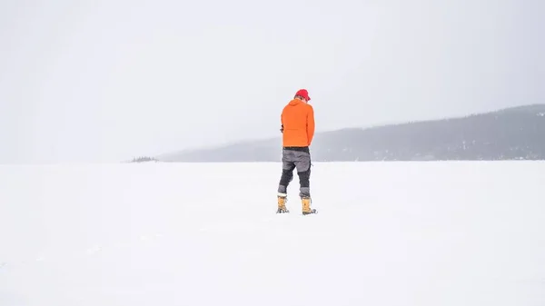 一个穿着橙色冬季夹克站在雪山上的男人 — 图库照片