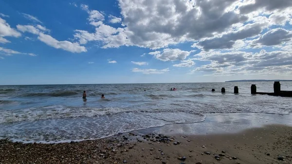 Живописный Вид Море Купающимися Людьми Голубым Облачным Небом — стоковое фото