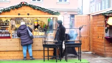 İnsanlar Noel süslemeleriyle süslenmiş küçük bir Noel pazarında alışveriş yapıyorlar.