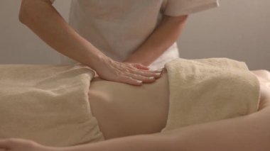 Bir masörün elleri yavaş çekimde müşterinin sırtına yumuşak cildinde yağ parıltılarıyla masaj yapıyor.