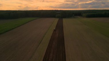 Gün boyunca bulutların altında yeşil bir manzaranın havadan çekilmiş görüntüsü.