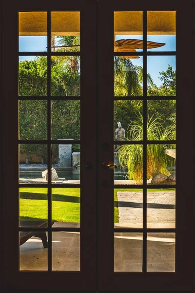 晴れた日にプールと手入れの行き届いた芝生で庭を眺めるフランスの窓 — ストック写真