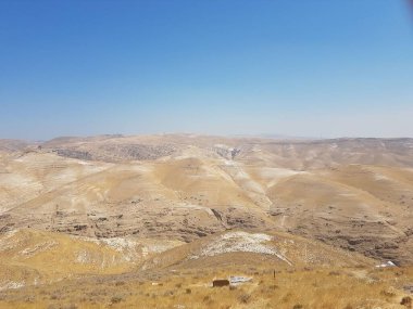 Bulutsuz gökyüzünün altındaki ıssız tepelerin manzarası.