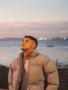 Akşam göl kenarında duran yakışıklı bir erkeğin yakın çekimi.