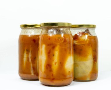 Doldurulmuş lahana dolu kavanozlar beyaz arka planda izole edilmiş domates sosu.