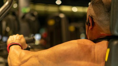 Spor salonunda beyaz kaslı bir adam antrenman yapıyor..