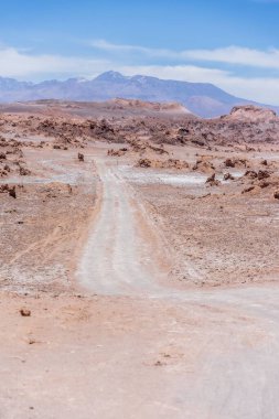 Şili 'deki Atacama Çölü' nde bulutlu mavi gökyüzünün altında bir yolun dikey görüntüsü.