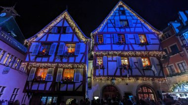 Fransa, Colmar 'da ışıklarla dekore edilmiş güzel binaların alçak açılı manzarası.