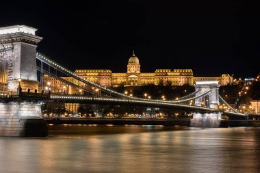 Aydınlatılmış binaların güzel bir görüntüsü ve Budapeşte, Macaristan 'da kıyıya yakın bir köprü.