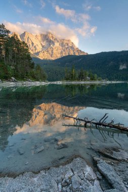 Güneşli bir günde kıyıda bir dağ sırası olan bir gölün dikey görüntüsü.