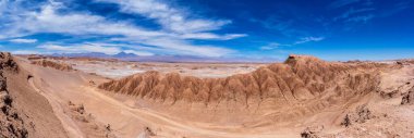Şili 'deki Atacama Çölü' nün bulutlu mavi gökyüzünün altında panoramik bir görüntüsü.