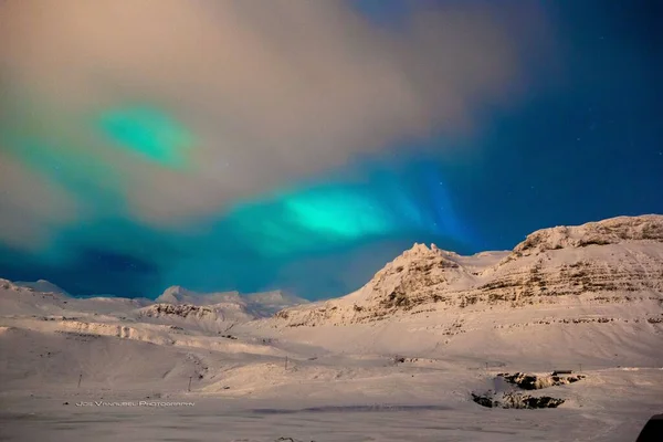 在覆盖着积雪的岩石山上 一幅明亮的北极光的风景画 — 图库照片