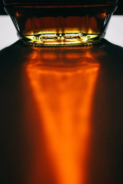 オレンジ色の光で抽象的な形を作る白い背景を反映した濃い茶色のカナダのメープルシロップのボトル — ストック写真
