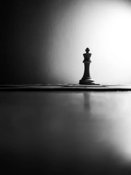 チェスボード上の王の作品のグレースケール垂直ショット — ストック写真