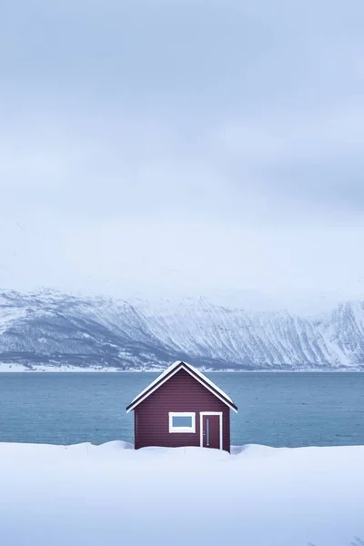挪威冬季湖畔一座小房子的竖向拍摄 — 图库照片