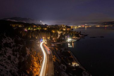 Tahoe Gölü 'nün bir manzarası gece vakti aydınlatılmış yollar ve binalarla çevrilidir.