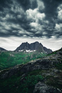 Norveç 'in kuzeyindeki kayalık dağın üzerinde fırtınalı bir gökyüzünün dikey görüntüsü