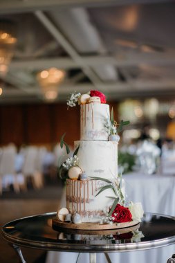 Güzel katmanlı bir düğün pastasının dikey çekimi. Makaronlar ve çiçeklerle.