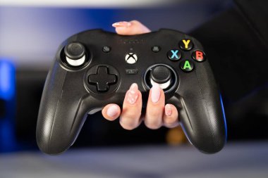 İzole edilmiş bir arkaplanda siyah bir xbox kumandasını tutan bir kişinin yakın plan fotoğrafı.