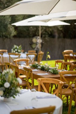 Güneşli bir günde sokakta küçük çiçeklerle süslenmiş ahşap bir festival masası.