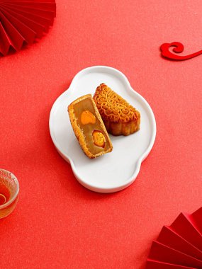 Kırmızı arka planda izole edilmiş beyaz plakalı bir ay pastasının dikey görüntüsü.