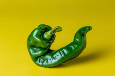 Sarı arka planda izole edilmiş yeşil biberin yakın çekimi.