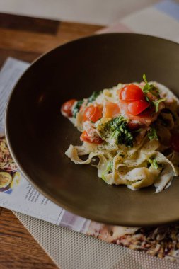 Restorandaki ahşap bir masada peynirli ve domatesli makarnanın yakın plan çekimi.