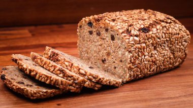 Dilimlenmiş çavdar ekmeğinin yakın plan çekimi. Ahşap bir yüzeydeki kabuğun üzerinde lezzetli tohumlar var.