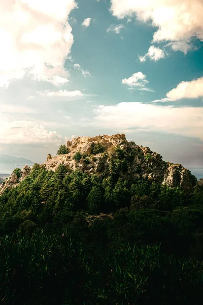 Pionowe Ujęcie Zielonego Pokrytego Skałą Wzgórza Pod Błękitnym Zachmurzonym Niebem — Zdjęcie stockowe