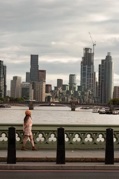 一个女孩从桥上走过 看着伦敦与泰晤士河交汇的城市景观的垂直镜头 — 图库照片