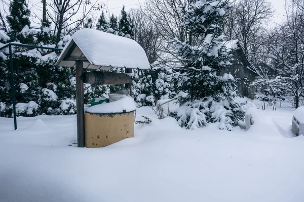 冬は裏庭に白いふわふわの雪で覆われた井戸 — ストック写真