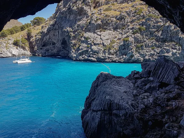 stock image A lovely view of huge rocks and lush trees surrounding the deep blue sea in Mallorca, Spain