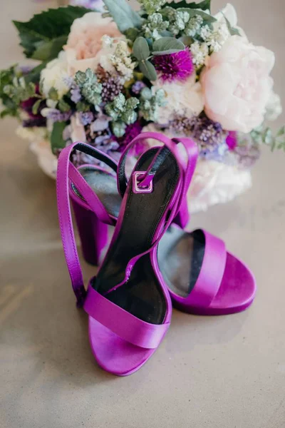 花束の横に紫色のかかとの垂直ショット — ストック写真
