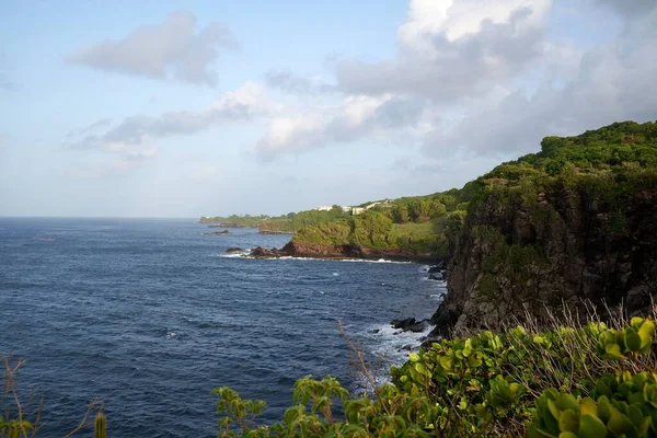 一个美丽的蓝色海水拍摄靠近岩石海岸与绿色悬崖 — 图库照片