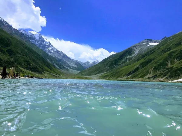 青い空の下 海岸や緑の丘の人々と美しい湖の水 — ストック写真