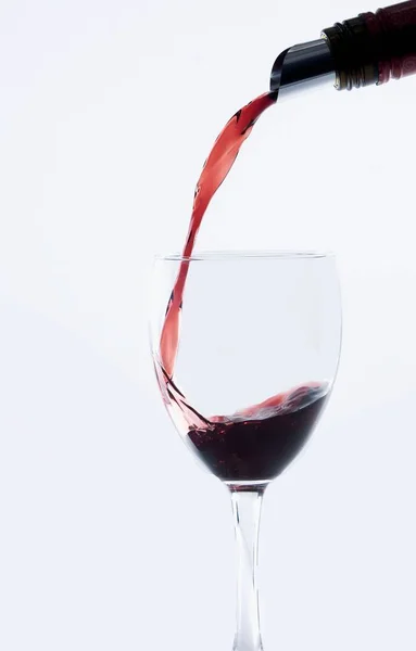 Ένα Κόκκινο Μπουκάλι Κρασί Ρίχνει Ένα Ποτήρι Κρασί Απομονωμένο Λευκό — Φωτογραφία Αρχείου
