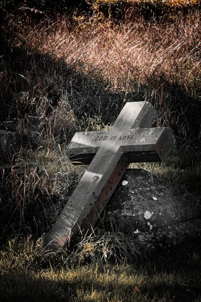 Pionowe Ujęcie Kamiennego Krzyża Opierającego Się Rozpadającym Się Grobie Napisem — Zdjęcie stockowe