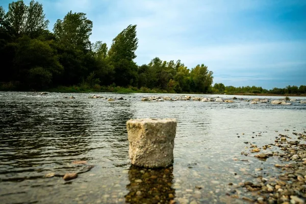 stock image A large stone at the shore of the River Drava in Croatia with thick trees in the background